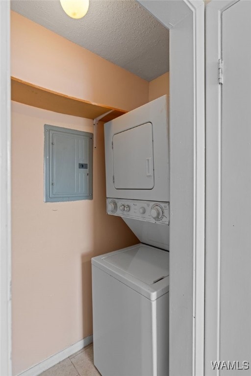 1500 W Beach Blvd Unit 212, Gulf Shores, AL 36542 - laundry area featuring stacked washer and dryer, electric panel, a textured ceiling, laundry area, and light tile patterned floors