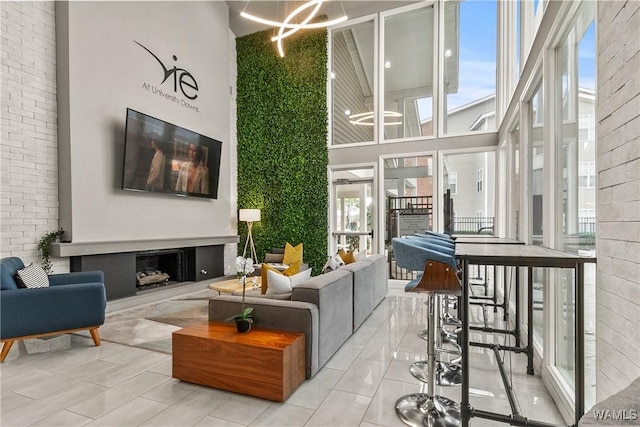 living room featuring a fireplace, an inviting chandelier, a healthy amount of sunlight, and a towering ceiling