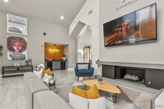 tiled living room featuring visible vents, baseboards, high vaulted ceiling, recessed lighting, and a fireplace with raised hearth