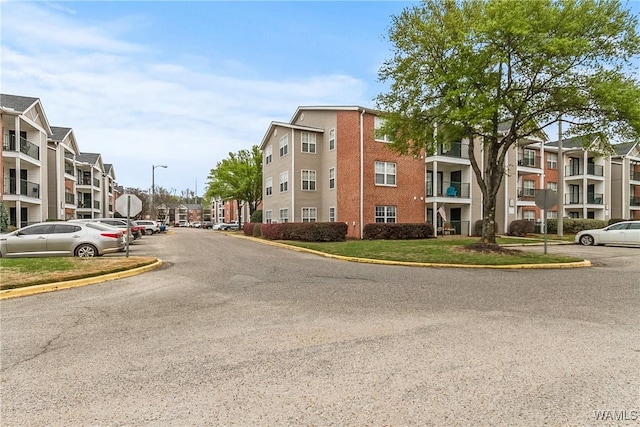 view of road with a residential view, traffic signs, curbs, and street lights