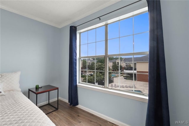bedroom featuring baseboards, crown molding, and wood finished floors