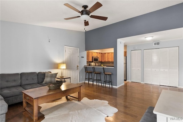 living area with baseboards, ceiling fan, visible vents, and wood finished floors