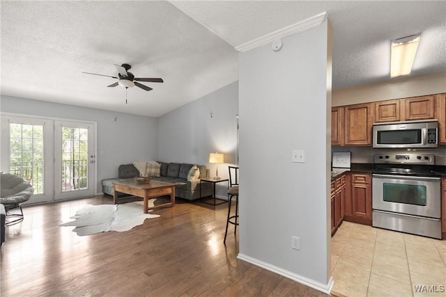 kitchen with brown cabinetry, open floor plan, ceiling fan, and stainless steel appliances
