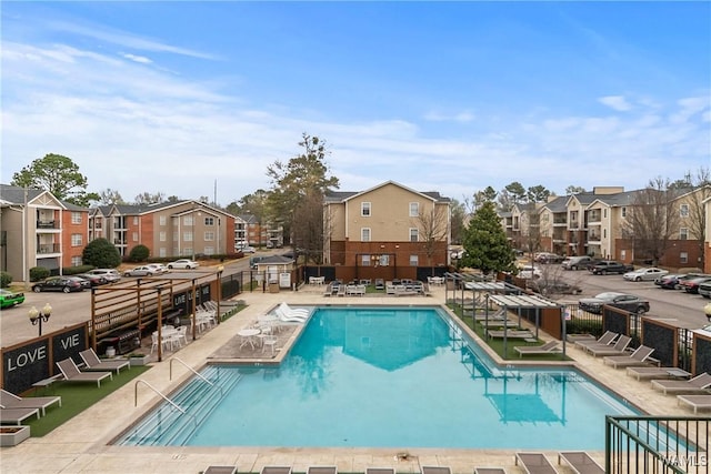 community pool with a residential view, fence, and a patio