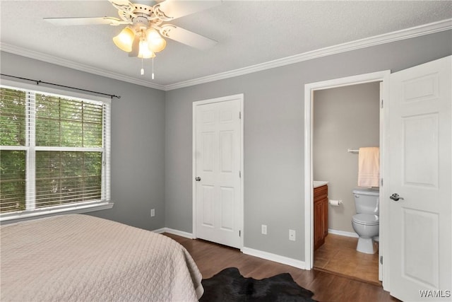 bedroom with crown molding, baseboards, dark wood-style flooring, and connected bathroom