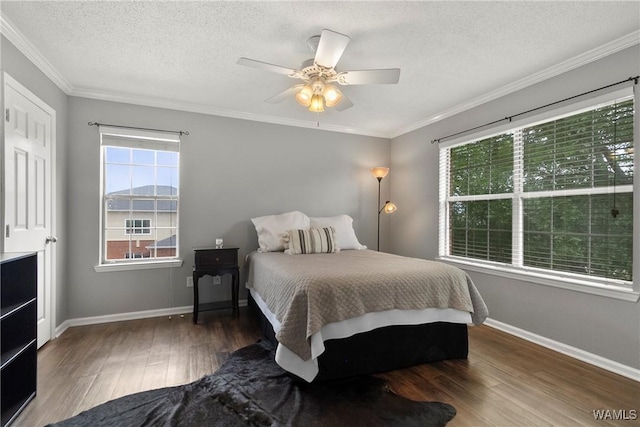 bedroom with baseboards, a textured ceiling, crown molding, and wood finished floors