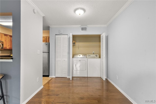 laundry area with washer and dryer, laundry area, a textured ceiling, wood finished floors, and visible vents