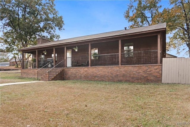 ranch-style home featuring covered porch, a chimney, a front lawn, and brick siding