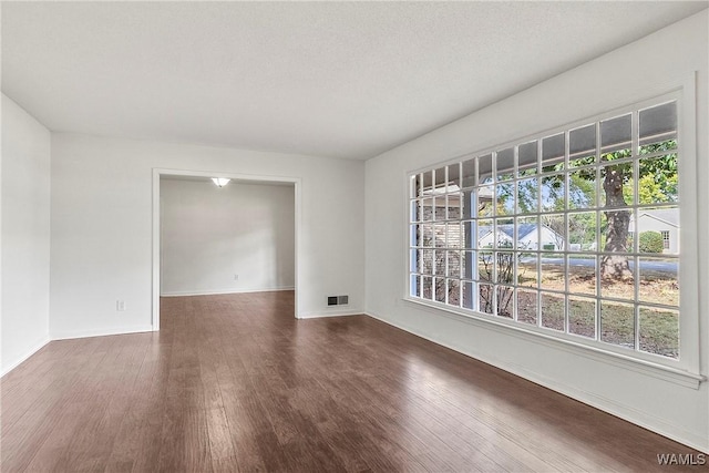 unfurnished room featuring a textured ceiling and dark hardwood / wood-style flooring