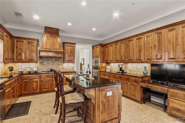 kitchen with a center island with sink, custom range hood, visible vents, dark stone counters, and a kitchen breakfast bar