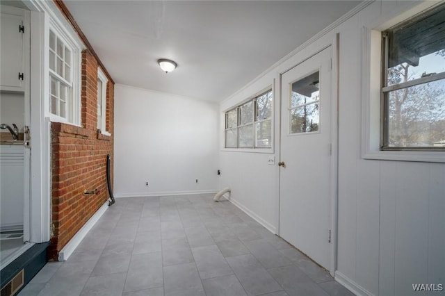 clothes washing area with plenty of natural light, brick wall, and ornamental molding