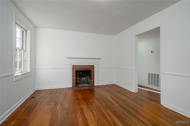 unfurnished living room featuring hardwood / wood-style flooring, a tile fireplace, and a wealth of natural light