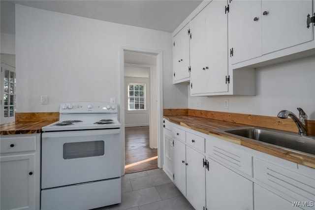 kitchen with electric stove, sink, white cabinets, and light tile patterned flooring