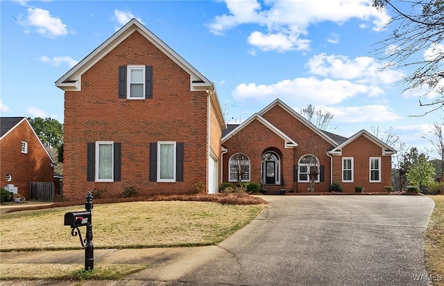 traditional-style house with brick siding, concrete driveway, and a front yard