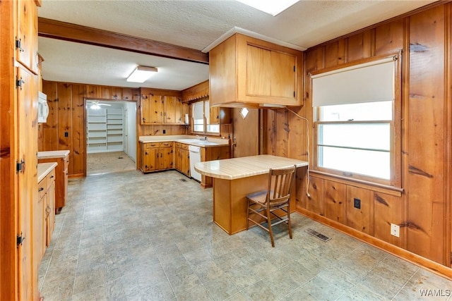 kitchen featuring visible vents, white appliances, wooden walls, a textured ceiling, and a sink