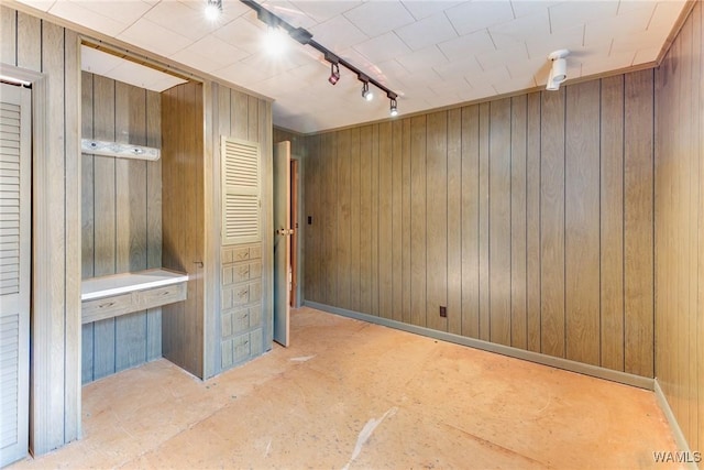 spare room with wood walls and track lighting