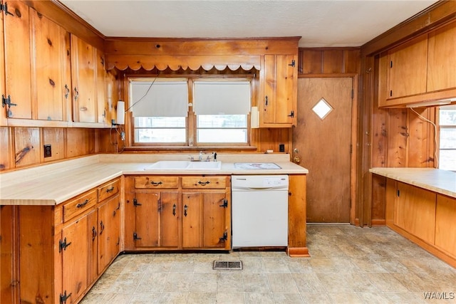 kitchen with light countertops, white dishwasher, brown cabinets, and a sink