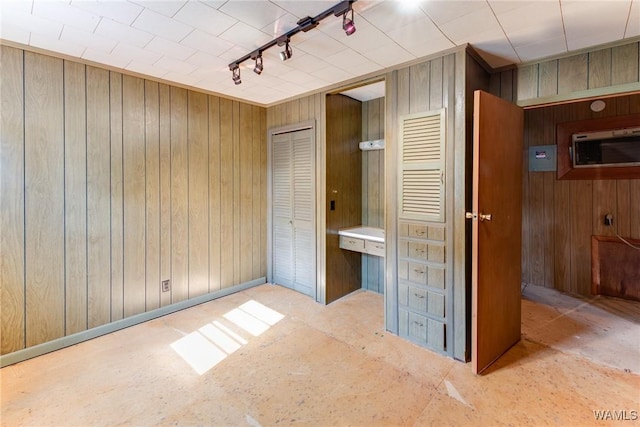 unfurnished bedroom featuring wood walls and track lighting