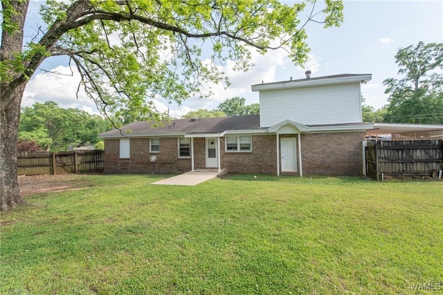 back of house with a yard, brick siding, and a fenced backyard