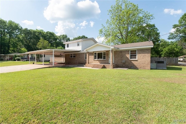 back of house featuring a lawn, brick siding, fence, concrete driveway, and an attached carport