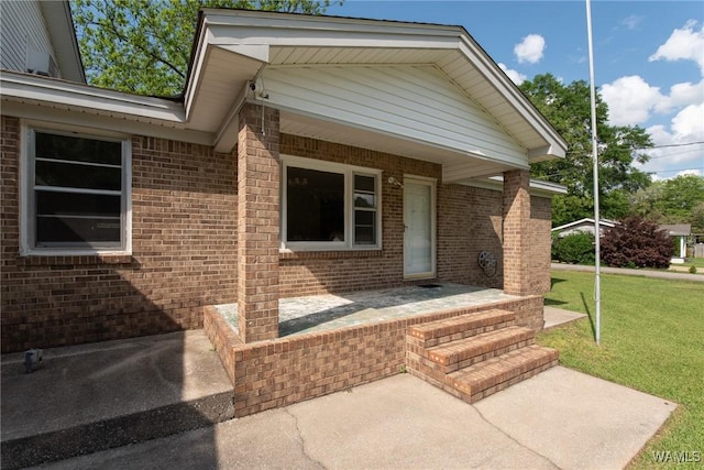 property entrance with a lawn and brick siding