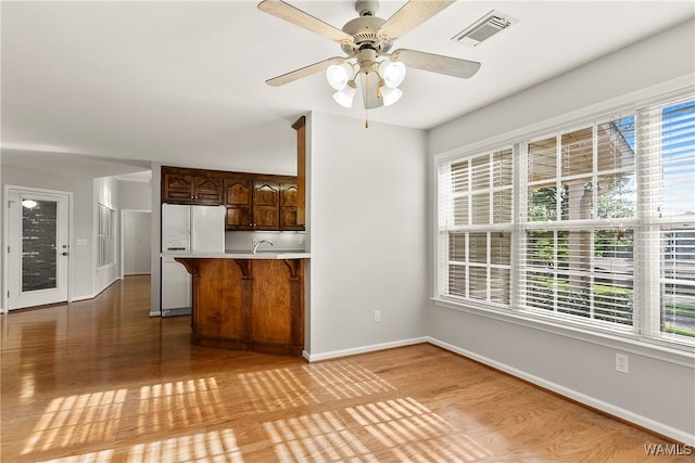 4713 Northwood Lake Dr E, Northport, AL 35473 - kitchen featuring white refrigerator with ice dispenser, a kitchen bar, light wood-style flooring, baseboards, and a peninsula