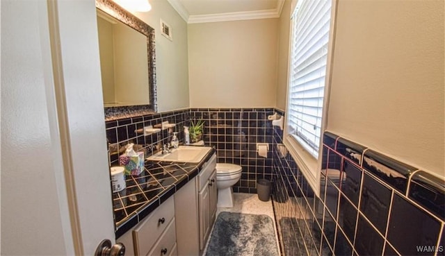 16584 Kathryn Lane Dr, Northport, AL 35475 - bathroom with toilet, vanity, ornamental molding, a wainscoted wall, and tile walls