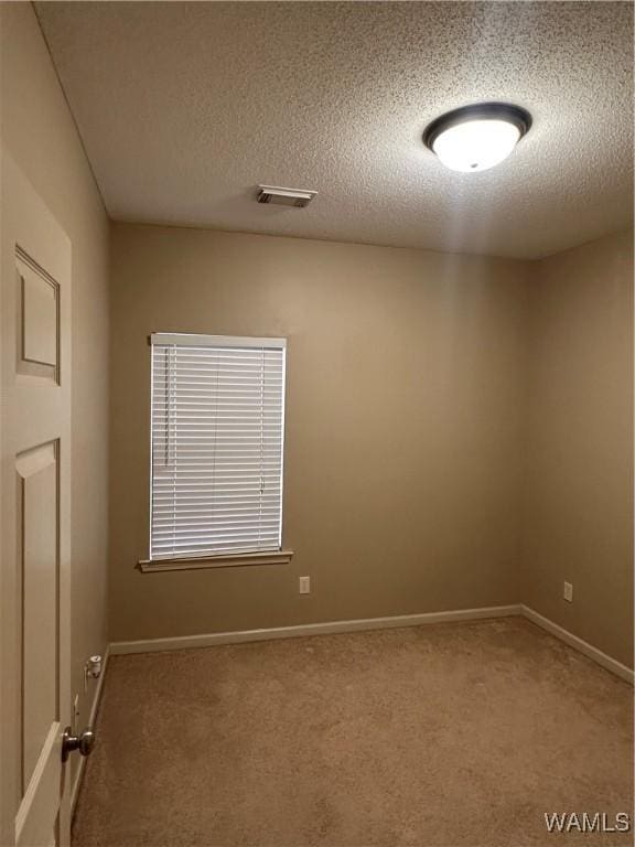 carpeted empty room with a textured ceiling