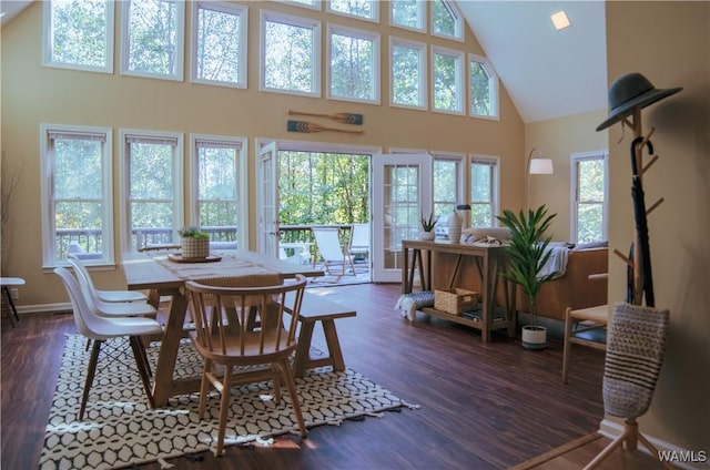 dining area featuring dark wood-style floors, high vaulted ceiling, and baseboards