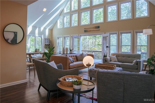 living room with dark wood-type flooring, high vaulted ceiling, and baseboards