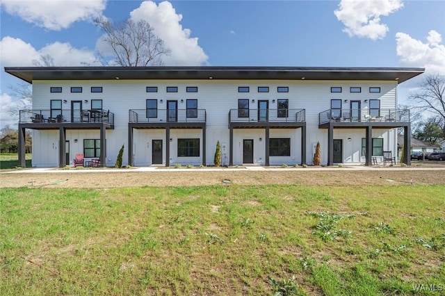 back of property featuring a balcony and a yard