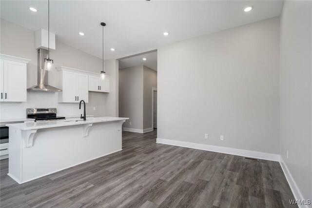 kitchen featuring white cabinetry, a breakfast bar area, stainless steel range with electric cooktop, hanging light fixtures, and a kitchen island with sink