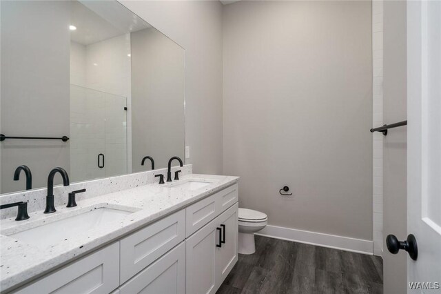 bathroom with toilet, hardwood / wood-style floors, vanity, and a shower with shower door