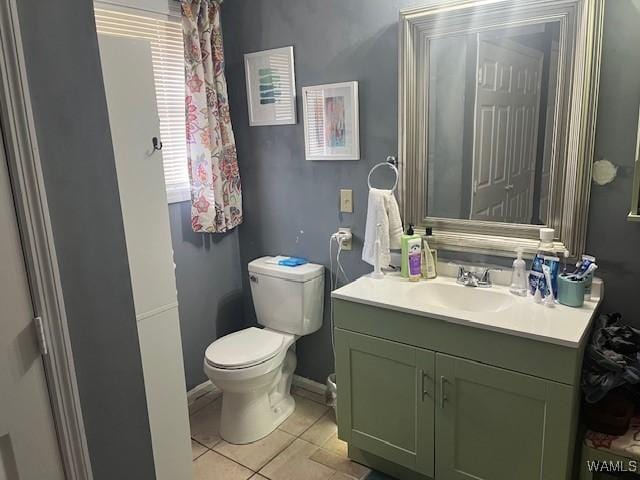 bathroom featuring toilet, tile patterned floors, baseboards, and vanity