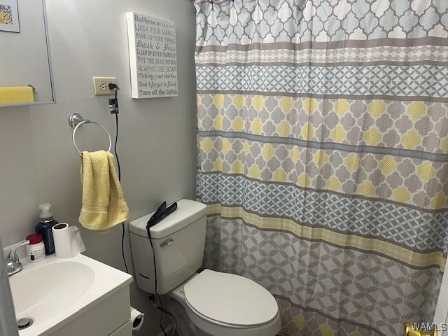 bathroom featuring toilet, a shower with shower curtain, and vanity