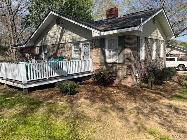 rear view of house featuring a chimney, a deck, and brick siding