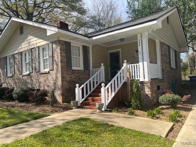 view of front of home with a chimney, crawl space, and brick siding