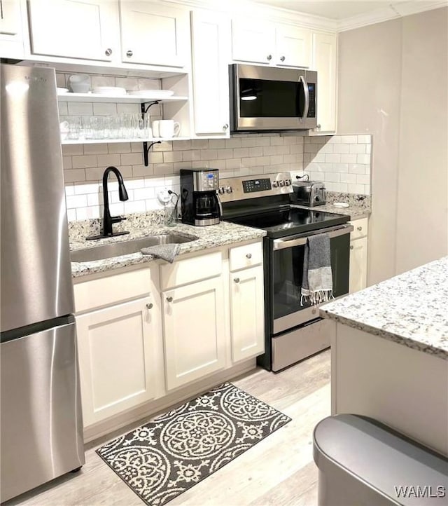 1402 9th St Unit 23, Tuscaloosa, AL 35401 - kitchen featuring stainless steel appliances, a sink, light wood finished floors, decorative backsplash, and ornamental molding