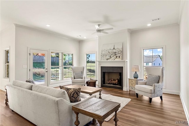 living room featuring a tile fireplace, hardwood / wood-style flooring, ceiling fan, and a healthy amount of sunlight