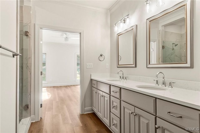 bathroom with vanity, a shower with door, ceiling fan, ornamental molding, and wood-type flooring