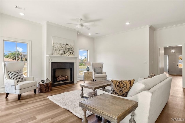 living room with ceiling fan, light hardwood / wood-style flooring, a healthy amount of sunlight, and ornamental molding