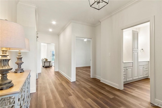 corridor with light wood-type flooring and crown molding