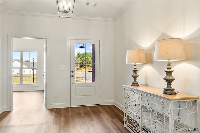 foyer entrance featuring wood-type flooring, an inviting chandelier, and ornamental molding