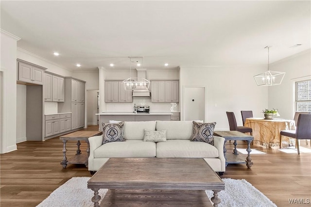 living room with an inviting chandelier, ornamental molding, and hardwood / wood-style flooring