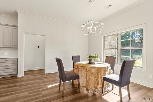 dining area featuring dark hardwood / wood-style flooring, ornamental molding, and a chandelier