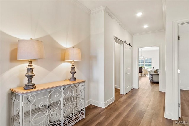 corridor with dark hardwood / wood-style flooring, a barn door, and crown molding