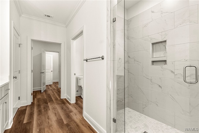 bathroom with toilet, wood-type flooring, crown molding, and a shower with shower door