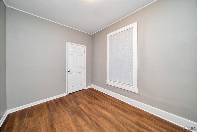 unfurnished room with baseboards, dark wood finished floors, and crown molding