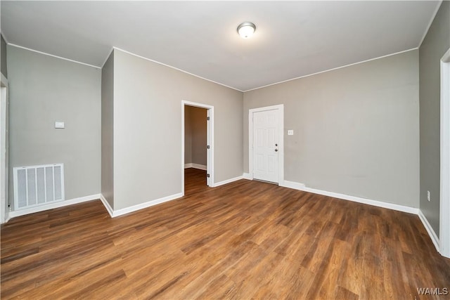 empty room with baseboards, visible vents, and wood finished floors