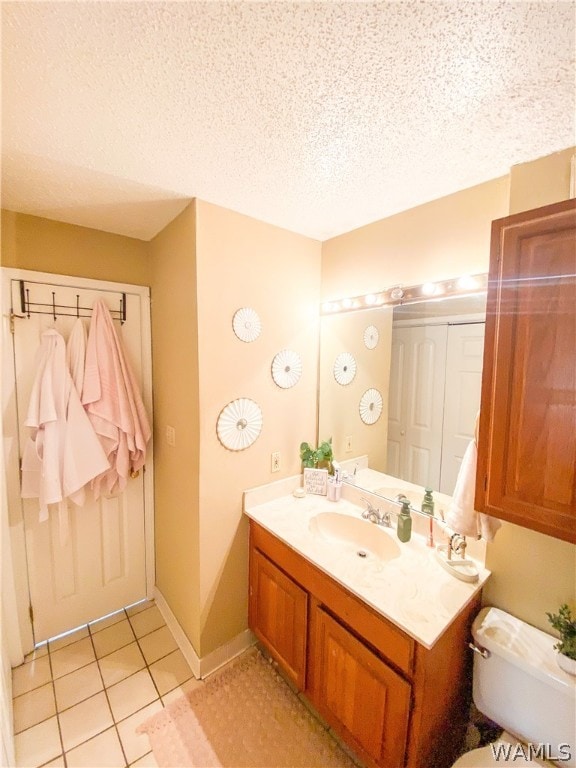 bathroom with toilet, a textured ceiling, vanity, and tile patterned floors